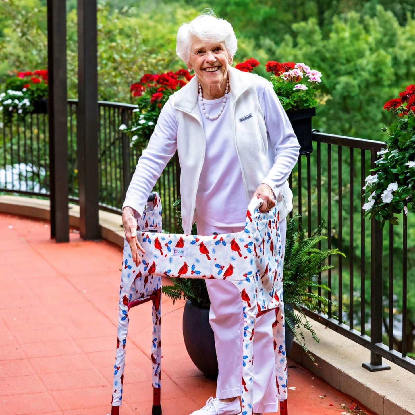 Woman outside showing off the Jover Walker Cover in Winter Birds featuring lively cardinals and festive holly berries on a snowy white background. With pockets and style, it's the perfect winter accessory.