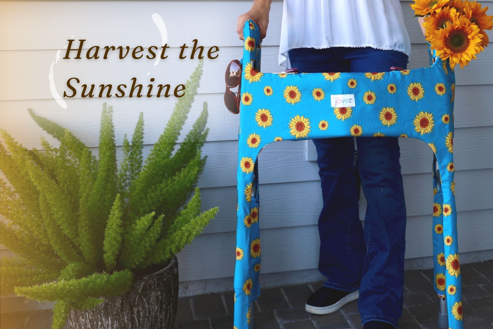 Woman on porch with a Sunflower Jover on standard walker; fresh sunflowers and sunglasses in outside pockets with text Harvest the Sunshine.