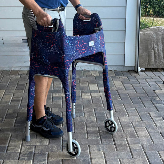 Man in blue shirt outdoors on a patio using a walker clad in a Fireworks Jover Walker Cove with grilling tools in the outside pocket.